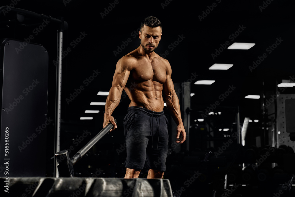 Shirtless bodybuilder carrying sledgehammer in gym. Shirtless bodybuilder carrying sledgehammer in gym.