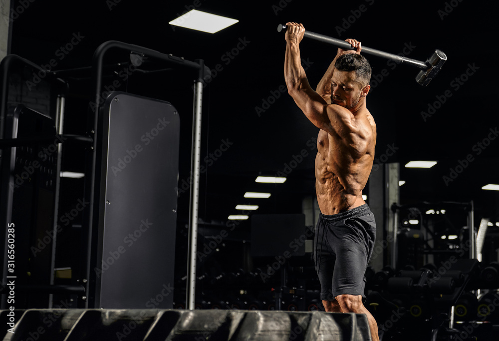 Fototapeta premium Crossfit sportsman hitting wheel with hammer.