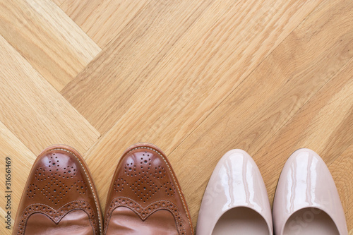 stylish leather shoes of a man and of a woman on wooden floor