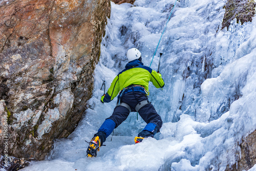 Fotografia Ice Climbing Man with an Ice Axe and Crampons on a Frozen Waterfall in the Tasch