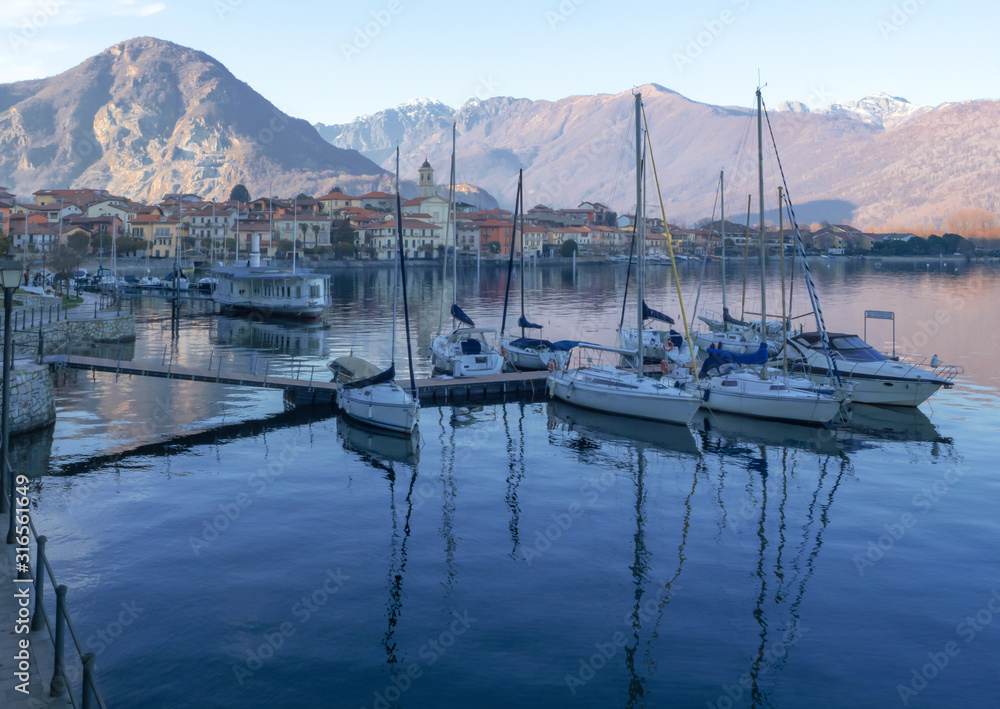 sailboats moored in front of feriolo, a characteristic town with a tourist vocation on the Piedmont coast of lake maggiore
