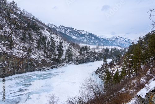 Landscape with snow-capped mountains and a freezing mountain river