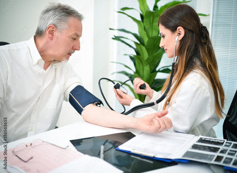 Doctor checking a patient blood pressure in her studio