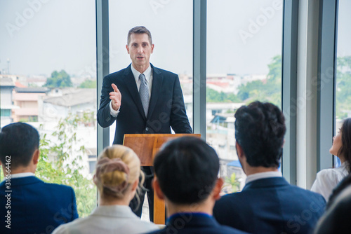 male speaker giving a talk on corporate business conference. Unrecognizable people at conference hall. Business seminar concept