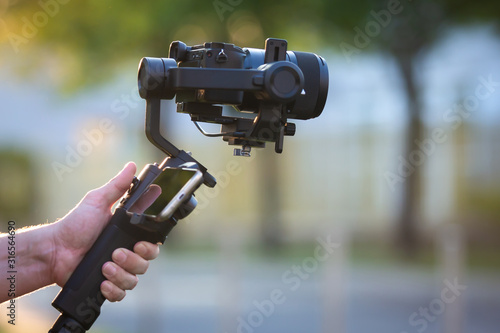 Man holding gimbal stabilizer outdoor.