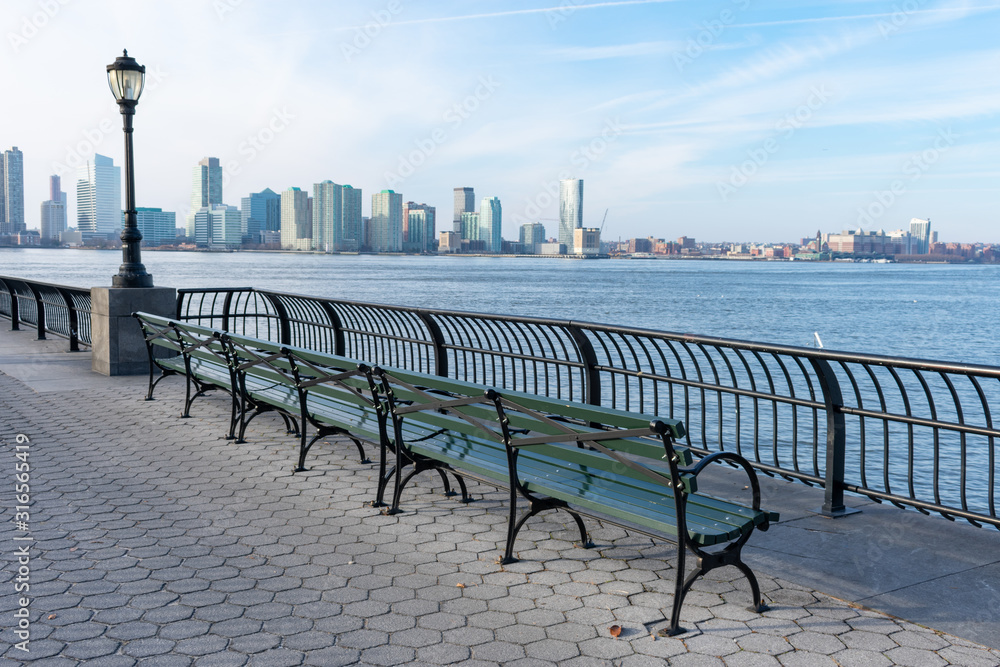 Empty Bench at Battery Park in New York City with a view of the Jersey City  Skyline along the Hudson River Stock Photo | Adobe Stock