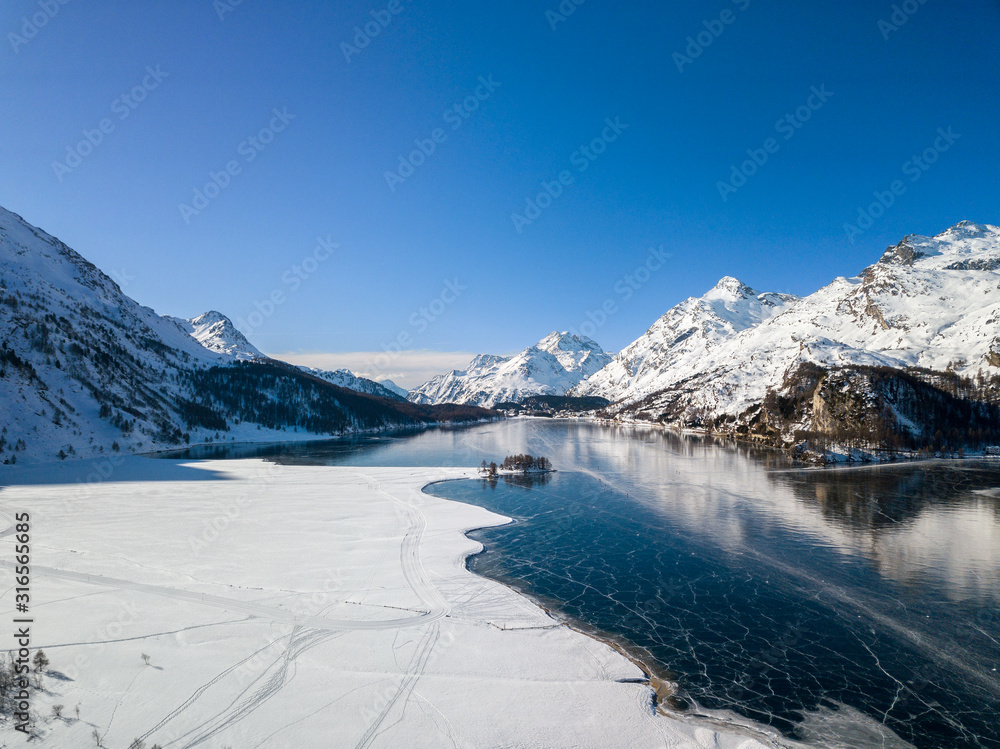 Obraz premium Aerial image of Insola, Maloja and Plaun da Lej on the frozen lake of Silsersee, St. Moritz, Switzerland