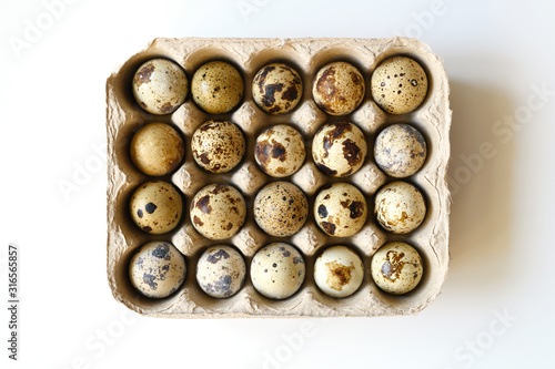 twenty quail eggs in a cardboard box on a white background