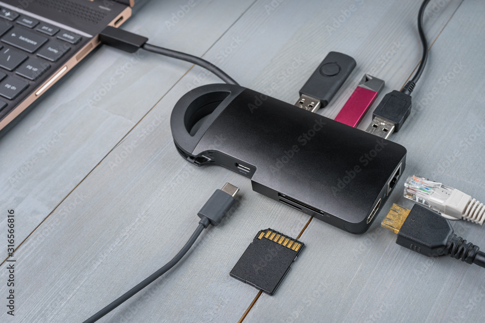USB Type C adapter or hub connected to the laptop with various accessories - pendrives, hdmi, ethernet, memory card, cables.