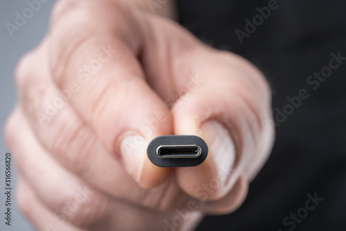 Obraz na płótnie USB Type C connector with a grey cable being held in hand. Shallow depth of field. w salonie