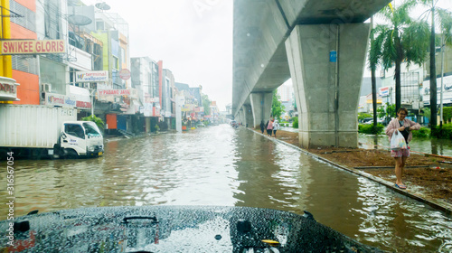 Car view of flooded road with pedestrians nearby
