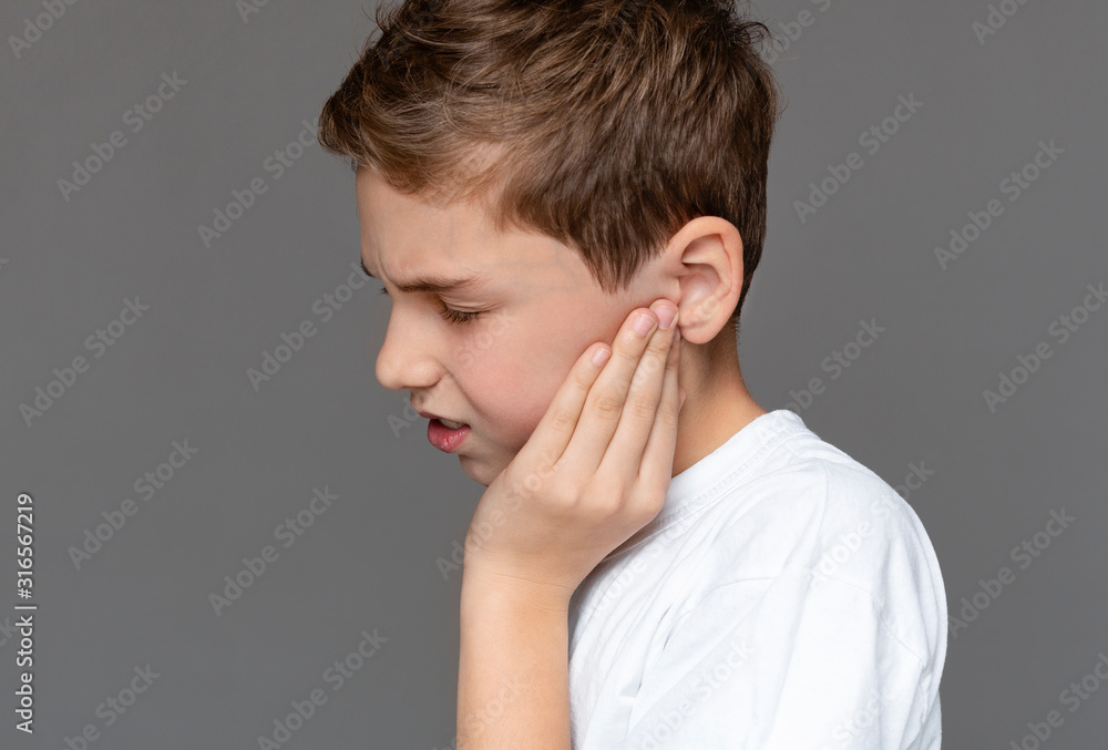 Teenage boy with pained expression holding his sore ears Teenage boy with pained expression holding his sore ears