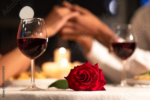 Rose Lying On Table, Loving Couple Holding Hands In Restaurant