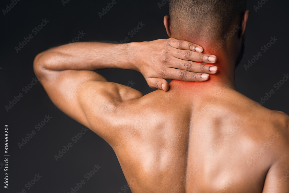 Unrecognizable shirtless afro guy suffering from pain in neck Unrecognizable shirtless afro guy suffering from pain in neck