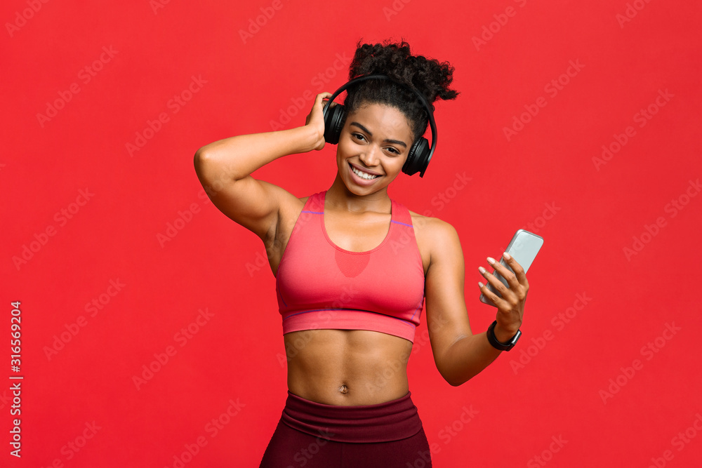 Joyful sporty woman listening to music while training