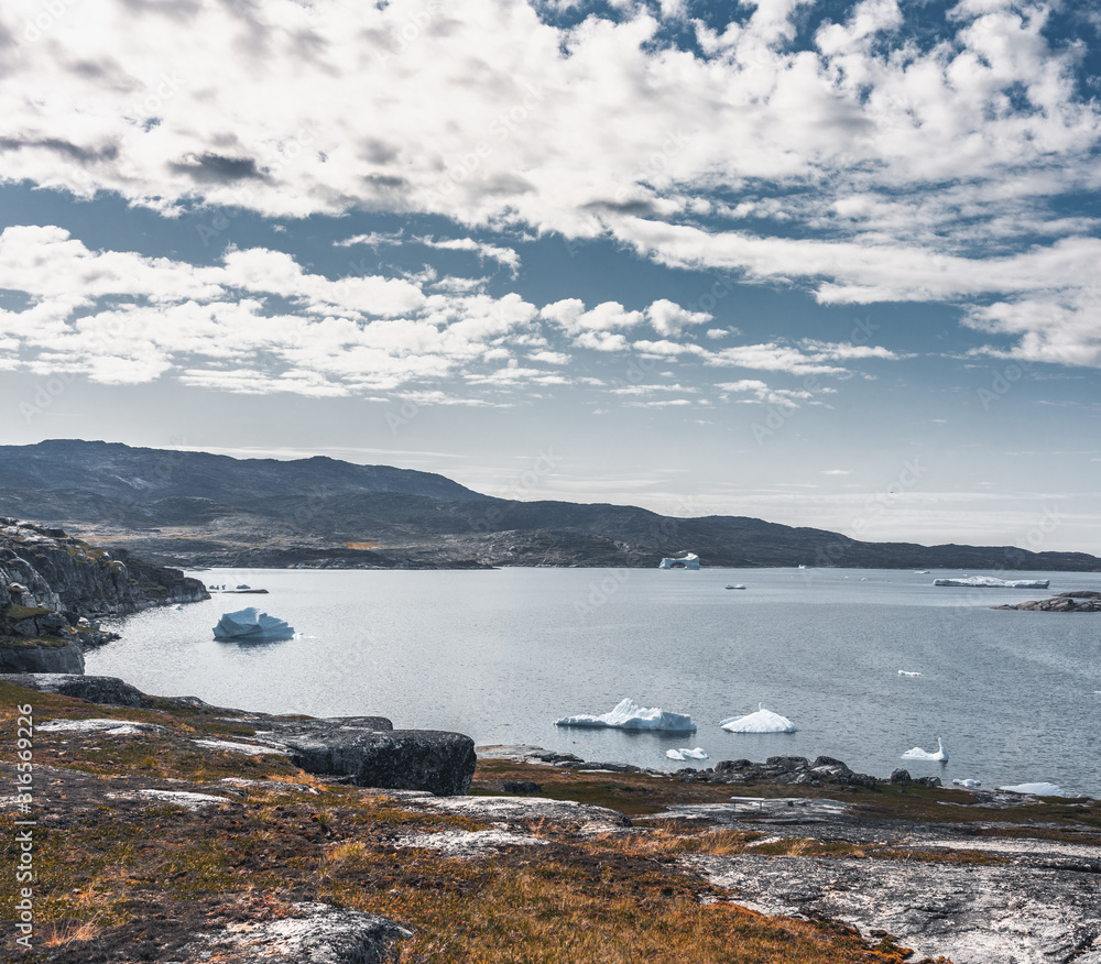 Magical arcticlandscape by Arctic Ocean in Greenland. Icebergs swimming in water. Blue sky on a summer day.