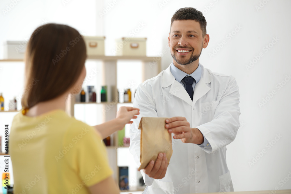 Fototapeta premium Pharmacist giving medicine to customer in drugstore