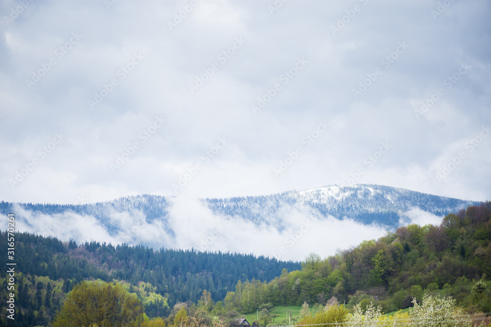 Fototapeta premium Snow covered mountain view on an early spring day with dramatic sky