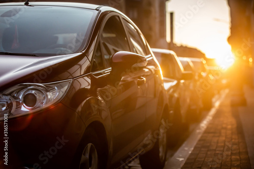 Cars parked on the side of the road, with sunset background.