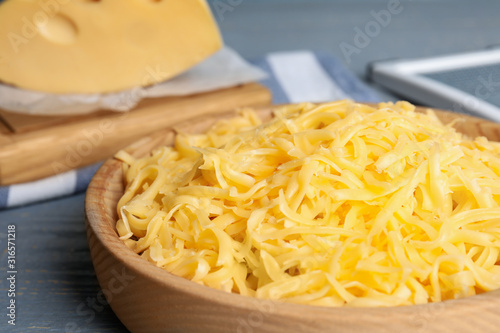 Tasty grated cheese on light grey wooden table, closeup