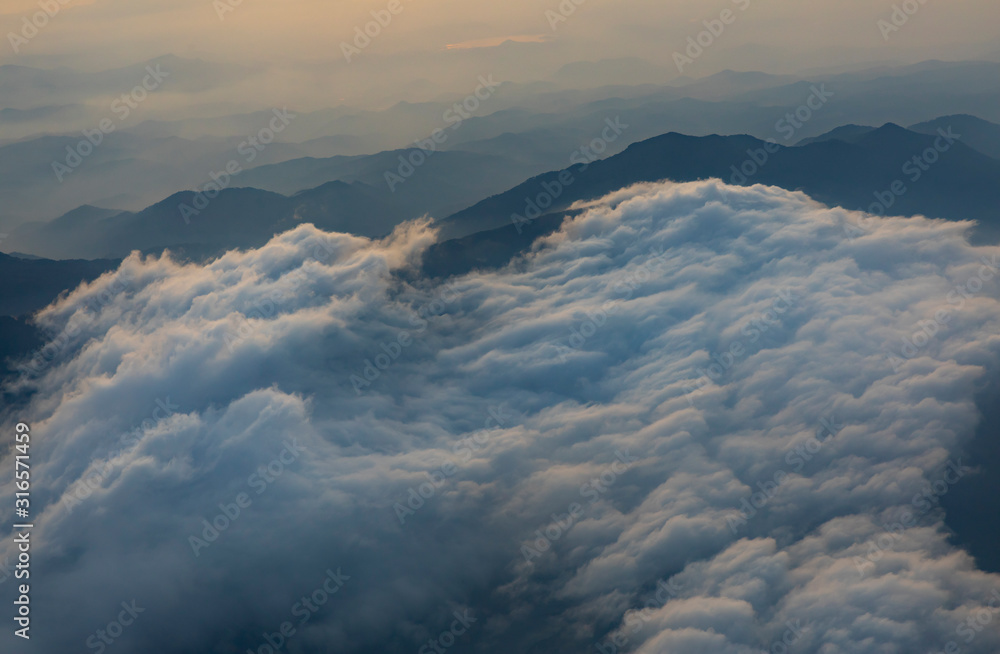 Flying over central highlands of Vietnam at dawn near the city of Da Lat. Clouds and mist reveal the  mountains below