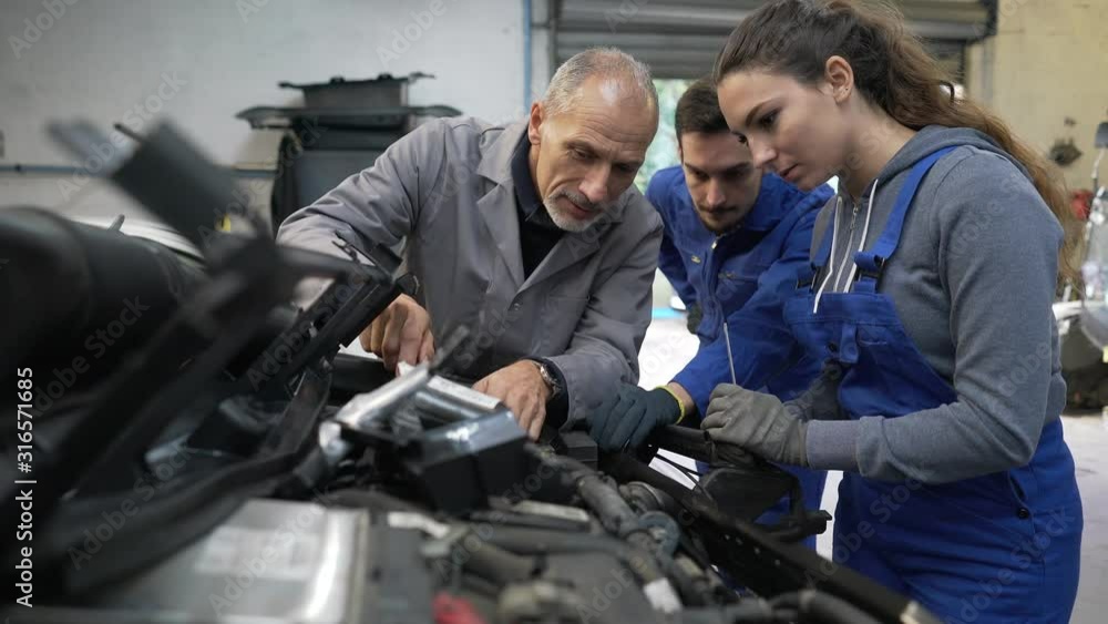 Instructor with trainees working on car engine Instructor with trainees working on car engine