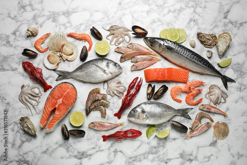 Fresh fish and different seafood on white marble table, flat lay