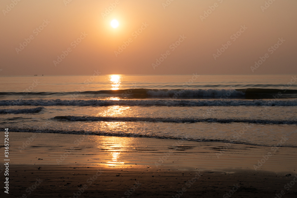 Nature background of seashore beach wave and coastline sand with sunset on water surface for holiday relaxation lifestyle concept