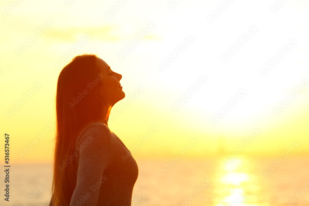 Woman breaths fresh air at sunset on the beach