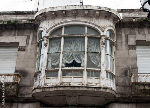 Old wooden white painted gallery windows with curtains in Vigo, Spain.