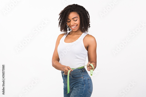 Portrait of african american woman measuring waist