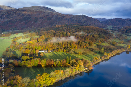 Breathtaking vibrant aerial drone landscape images over Coniston Water at sunrise on beautiful Autumn Fall morning