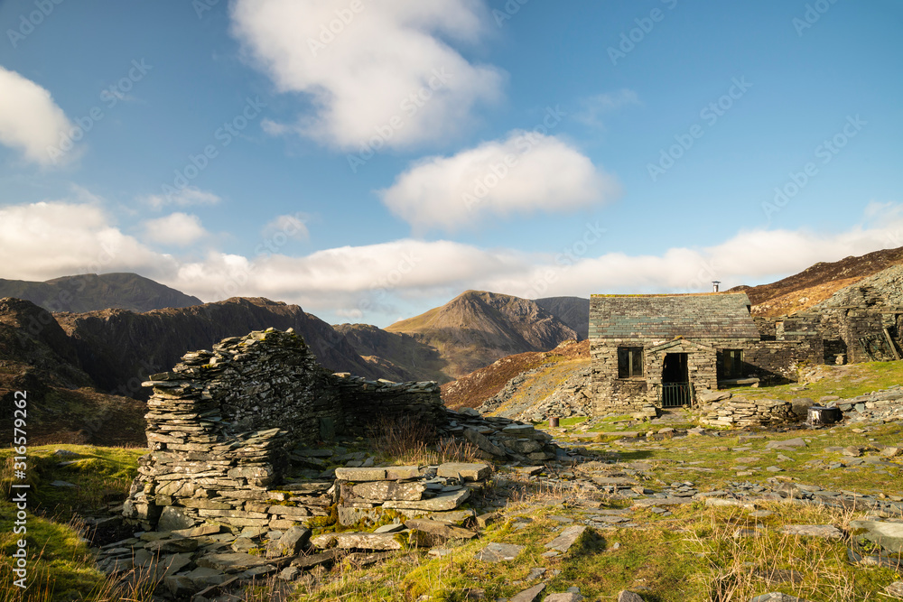 Obraz premium Autumn Fall landscape image of old bothy in Lake Districtr mountains near Buttermere with Haystacks and High Stiel in the distance