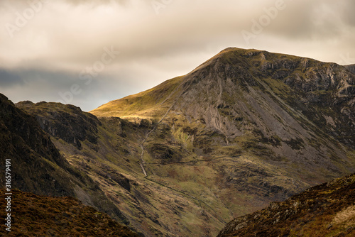 Epic Autumn Fall landscape image of mountain peaks in Lake District near Buttermere with gorgeous light across ridge