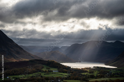 Majestic sun beams light up Crummock Water in epic Autumn Fall landscape image with Mellbreak and Grasmoor