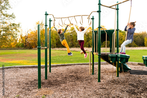 Young girls crossing the monkey bars at a park playground photo