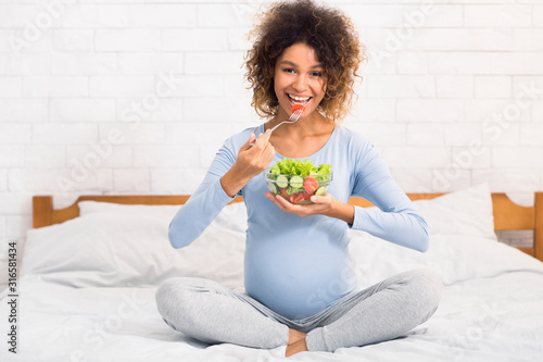 Pregnancy  healthy food concept. Afro woman eating vegetable salad