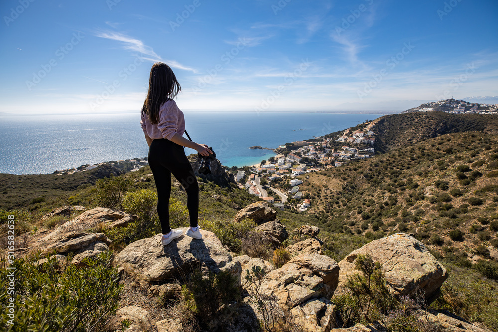 Beautiful woman photographer standing on a cliff holding a professional camera