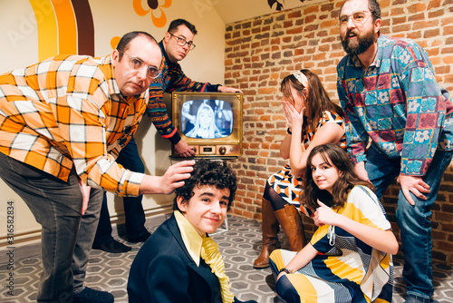 une famille regardant la télévision. Une famille des années 70 devant la télévision. Un groupe d'amis vintage. Des amis durant les années 70. Ambiance de famille rétro. Regarder la télévision. photo