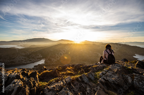 Beautiful woman standing on a cliff during sunset at Cap de Creus, Spain