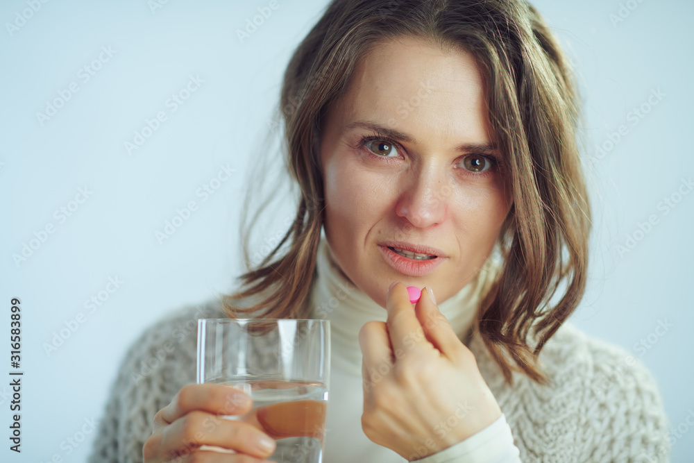 sick elegant housewife with cup of water eating pill sick elegant housewife with cup of water eating pill