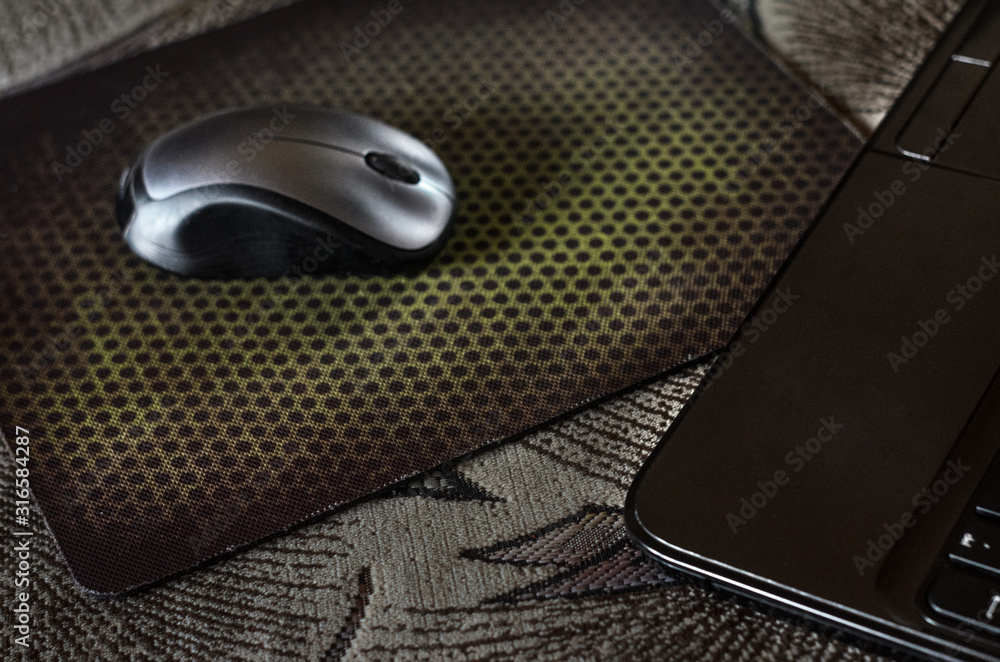 A laptop and a mouse pad and another phone on the couch. A laptop and a mouse pad and another phone on the couch.