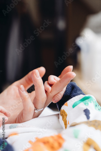 Newborn holding mother's hand. Closeup photography of hands. 