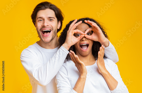 Man making funny glasses with fingers to his girlfriend