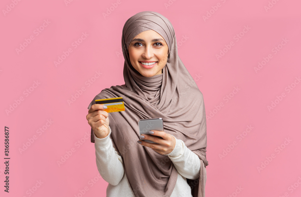 Happy islamic lady in hijab with credit card and smartphone Happy islamic lady in hijab with credit card and smartphone