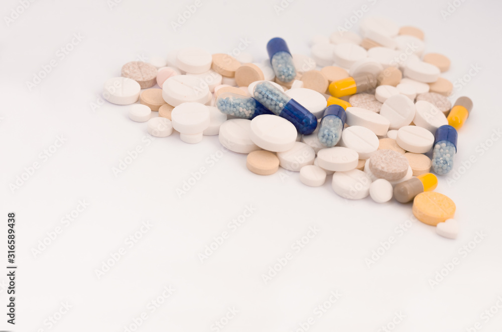 Heap of colorful pills in the shape of a heart, tablets and capsules on white background. Drug prescription for treatment medication health care concept, top view with copy space.