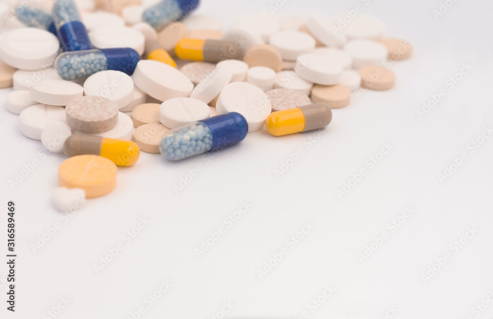 Heap of colorful pills in the shape of a heart, tablets and capsules on white background. Drug prescription for treatment medication health care concept, top view with copy space.