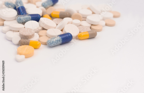 Heap of colorful pills in the shape of a heart, tablets and capsules on white background. Drug prescription for treatment medication health care concept, top view with copy space.