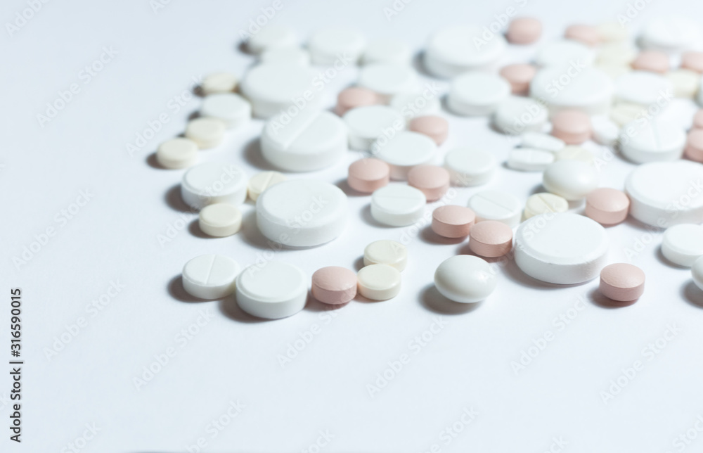 Heap of pills, pharmaceutical medicine tablets and capsules on white background. Drug prescription for treatment medication health care concept, top view with copy space.