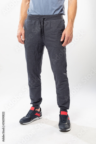 athletic man in sweatpants and sneakers on a white background, men's sports pants close-up